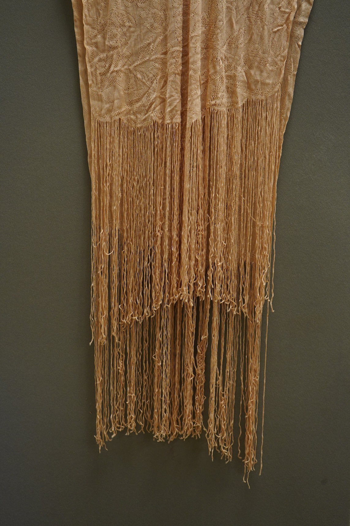 A 1920’s-30’s silk stockinette fringed ladies open sided knitted tabard, sides 56cm long not including fringe. Condition - front point of V slightly worn.